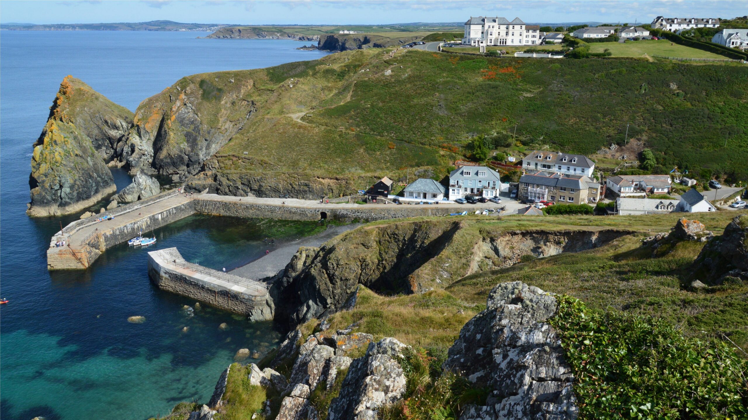 Aerial view of Mullion Cove harbour, coastal buildings and dramatic cliffs in Cornwall.